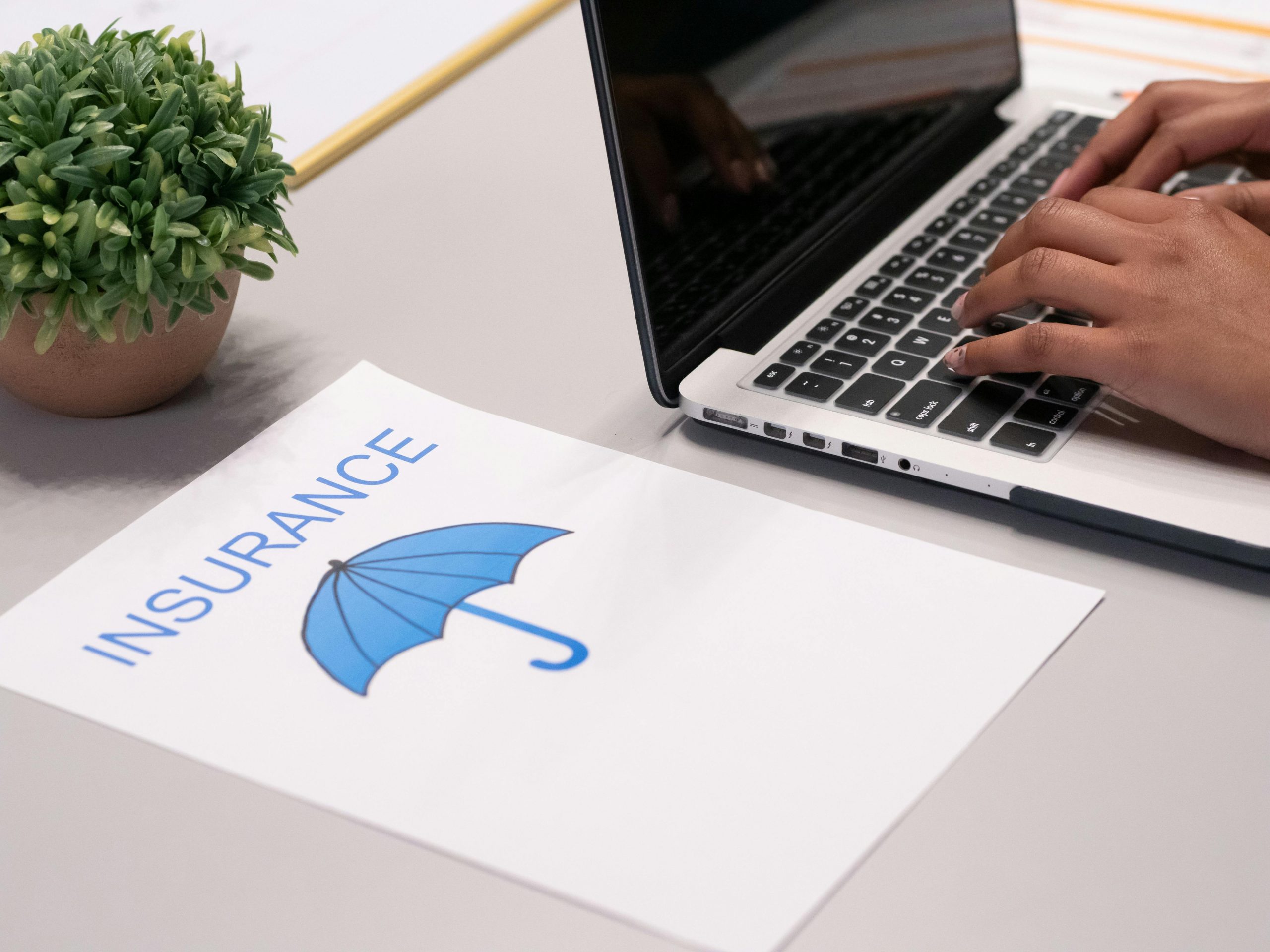 paper with an umbrella image and the word "insurance" next to a laptop